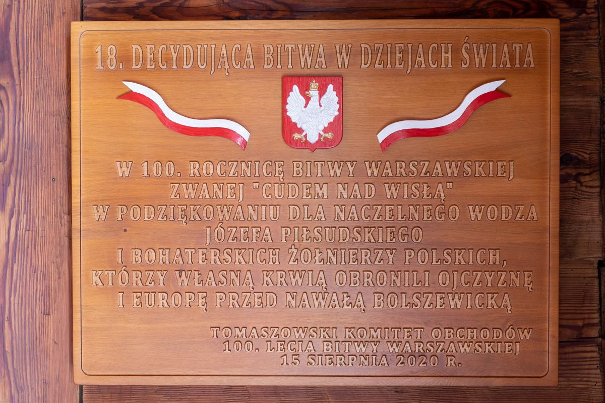 Tablica z okazji 100 Rocznicy Bitwy Warszawskiej. Wykonana z drewna w 2020 r. o wymiarach 61 cm x 81 cm. Kruchta główna.